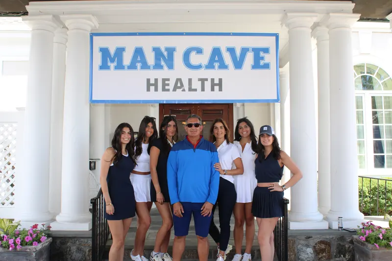 The Milana family at the 11th Annual Golf Outing beneath the Man Cave Health banner